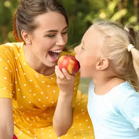 Mum and daughter eating an apple on a picnic
